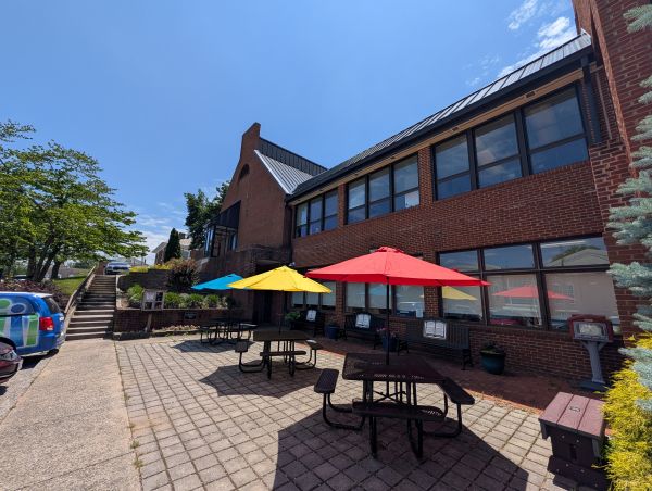 Photo of the patio at CCPL, including the benches, umbrellas, pantry, and seed library.